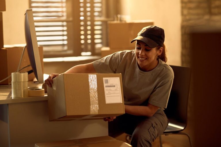 repartidora-feliz-preparando-cajas-carton-envio-mientras-trabaja-oficina_637285-6317